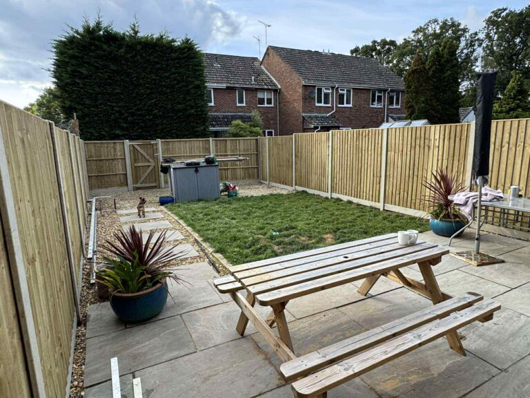 New fencing around a patio garden with lawn and picnic bench