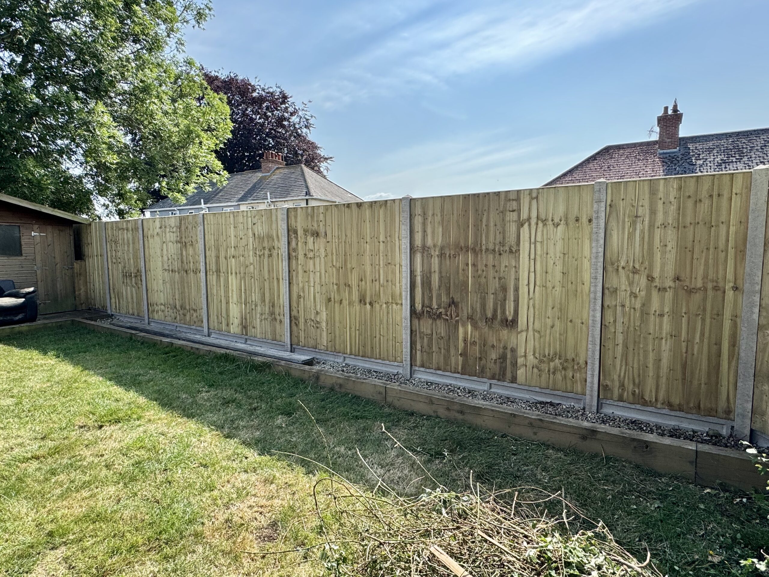 Long run of new timber fencing on concrete posts along a lawn