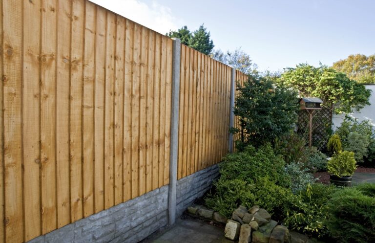 Closeboard fence on concrete gravel boards beside a planted border