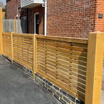 Slatted horizontal screen fence on a low brick wall