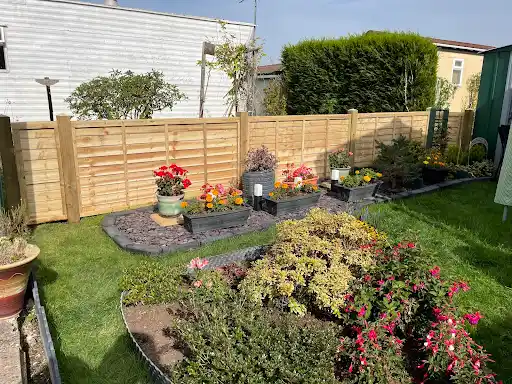 Horizontal slatted fence behind a planted garden and lawn